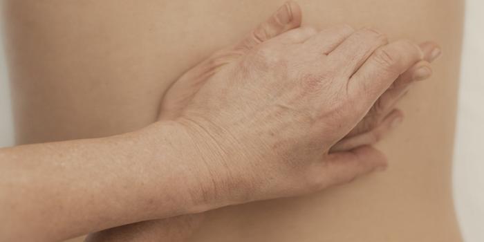 A therapist's forearm drawn slowly across an oiled lower back