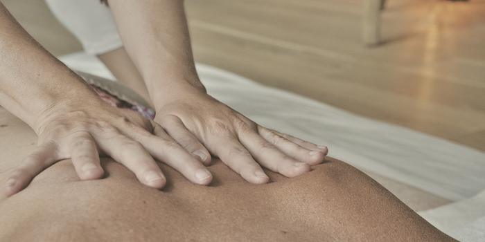 A therapist's hands pressing down at floor level, working on a mat